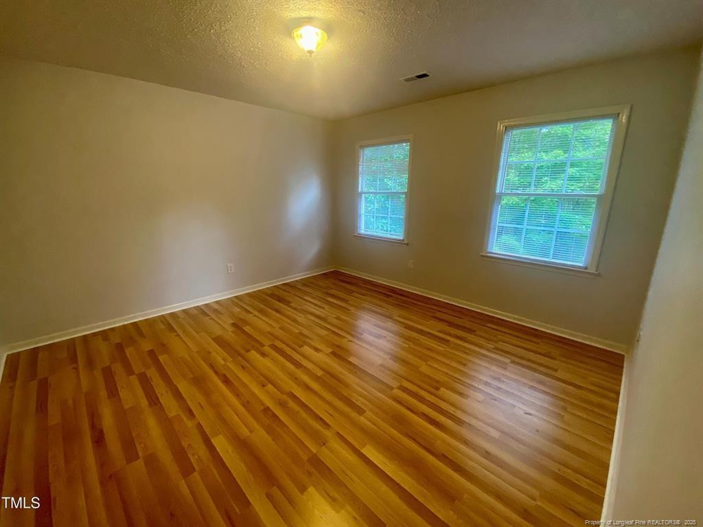 4219 Arbutus Drive, Unit A Raleigh, NC 27612 - Photo 16 of 30 a view of an empty room with wooden floor and a window