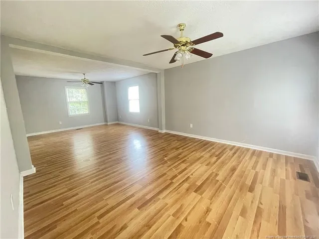 a view of empty room with wooden floor and fan
