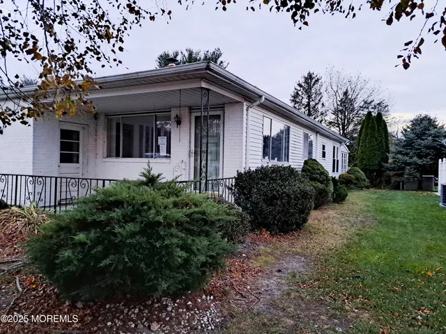 a view of a house with a small yard plants and a large tree