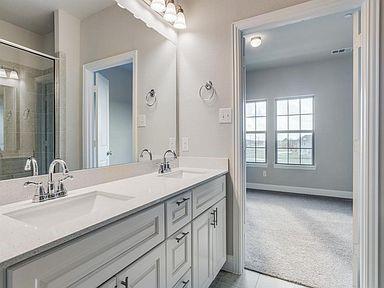 4717 Ladrillo Lane McKinney, TX 75070 - Photo 19 of 24 Bathroom featuring light colored carpet, double vanity, light tile patterned flooring, and a shower with door