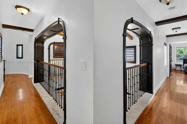 a view of a hallway with wooden floor and a bathroom