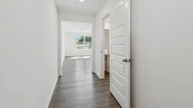 a view of a hallway with wooden floor and a bathroom