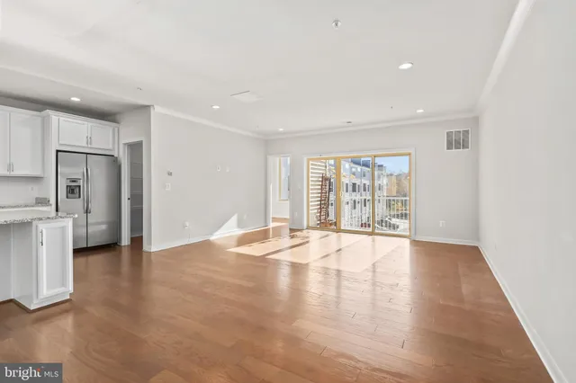 a living room with stainless steel appliances furniture and a kitchen view