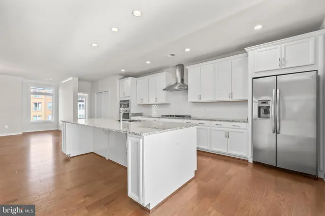 a kitchen with stainless steel appliances granite countertop a refrigerator sink and white cabinets