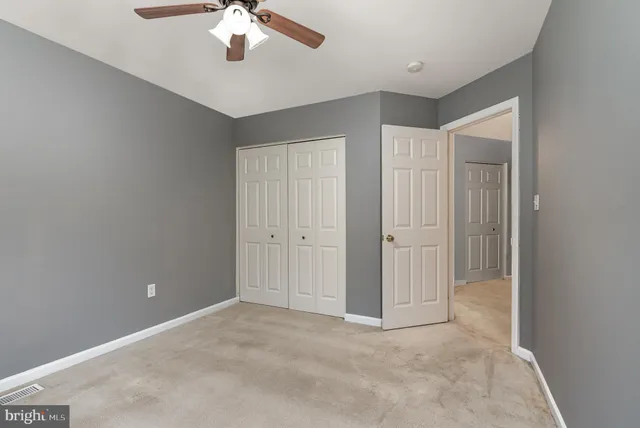 a view of an empty room with a chandelier fan