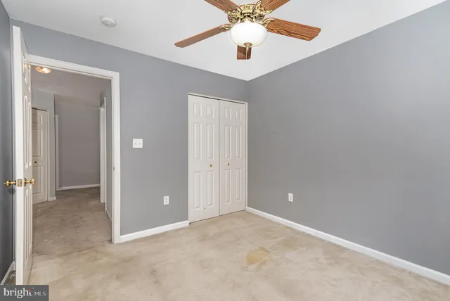 an empty room with closet and a chandelier fan