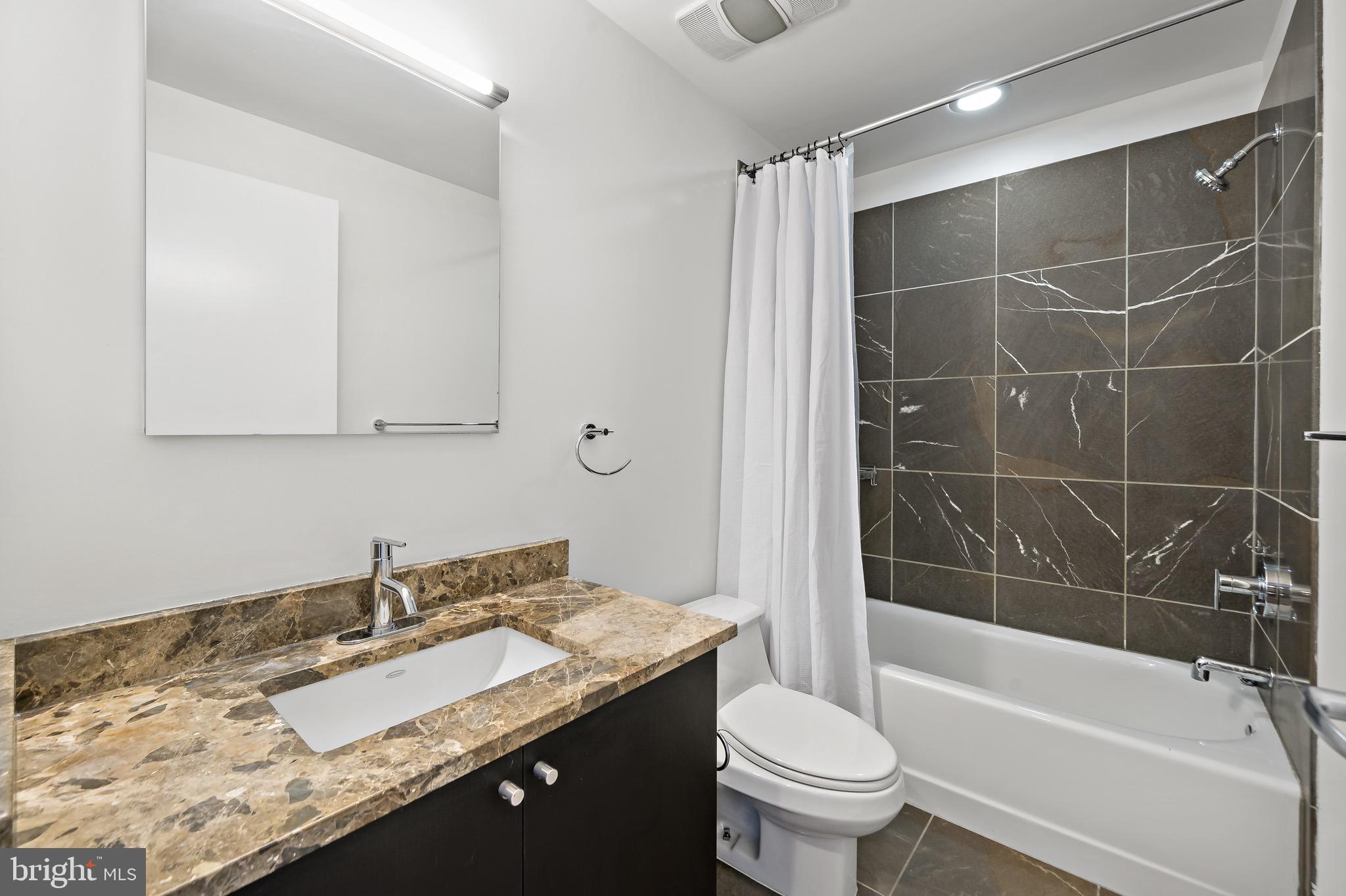 1101 Locust Street, Unit 7I Philadelphia, PA 19107 - Photo 18 of 27 a bathroom with a granite countertop sink a toilet and bathtub