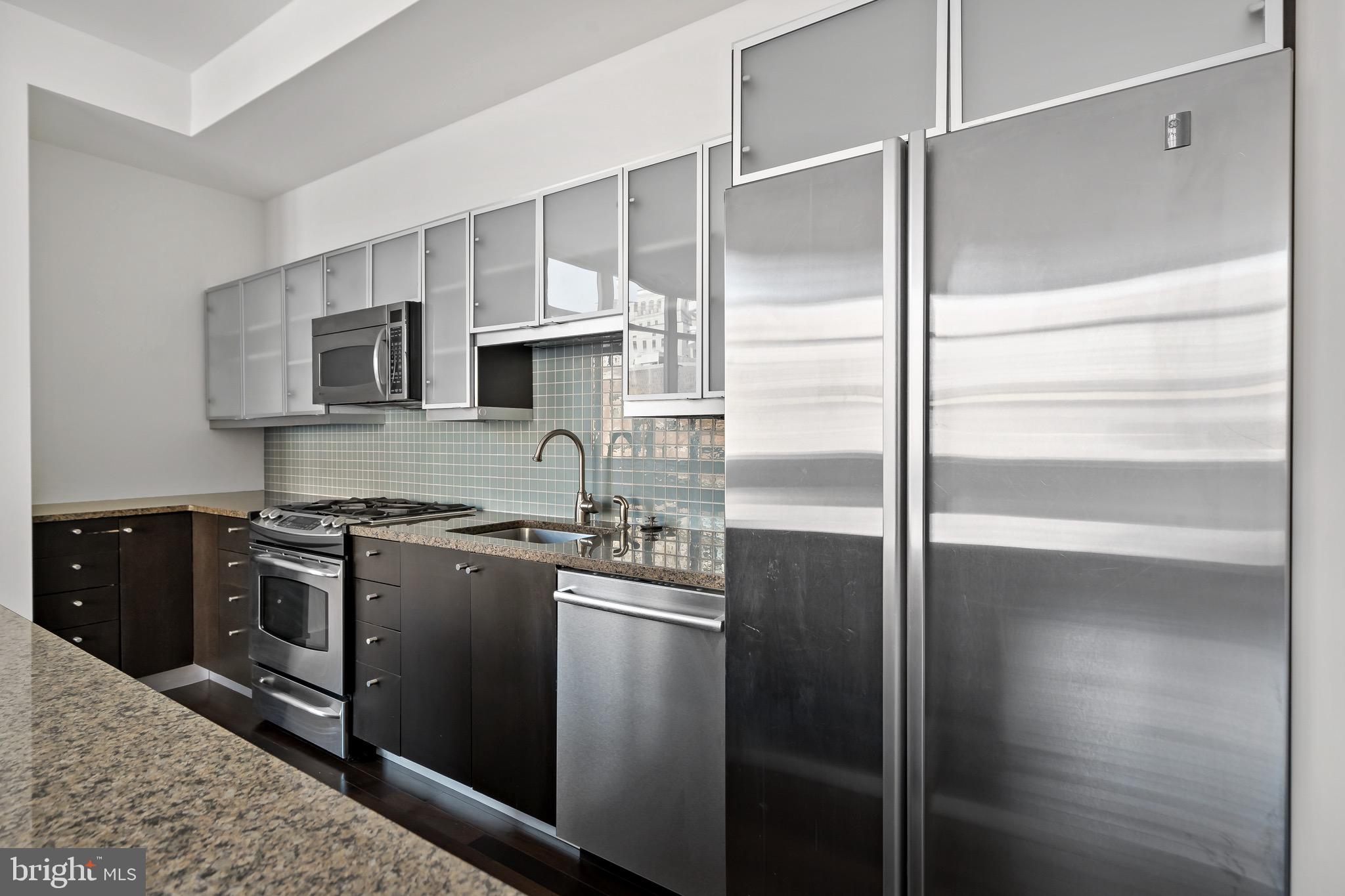 1101 Locust Street, Unit 7I Philadelphia, PA 19107 - Photo 8 of 27 a kitchen with kitchen island granite countertop a refrigerator stove and sink
