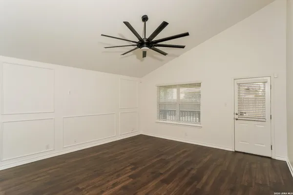 an empty room with wooden floor fan and windows