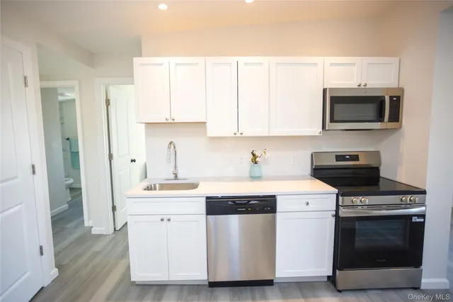 a kitchen with white cabinets stainless steel appliances and sink