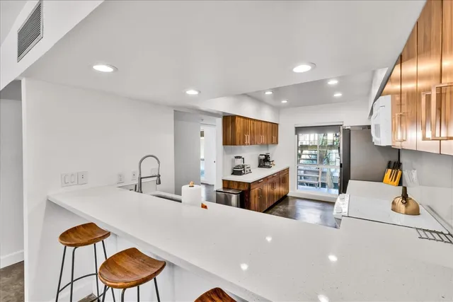 a large kitchen with stainless steel appliances a large counter top space a sink a couch and window