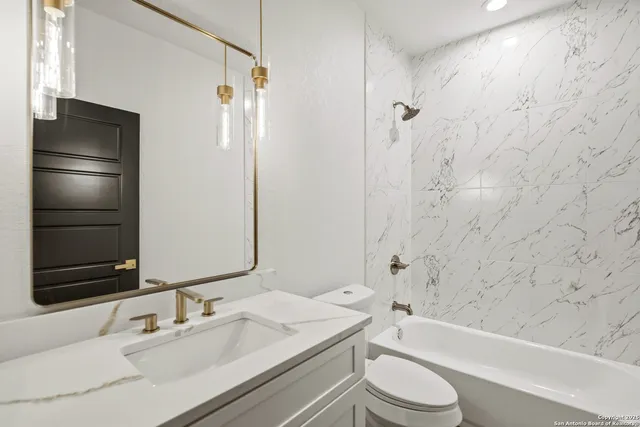 a bathroom with a bathtub shower sink vanity mirror and toilet