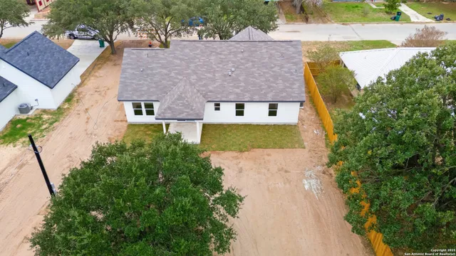 an aerial view of a house with a yard and trees all around