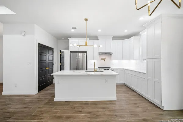 a large white kitchen with kitchen island a island a stove a cabinets and a sink