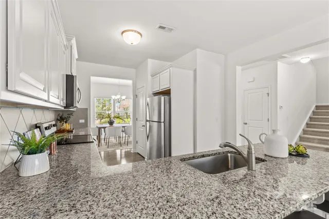 a kitchen with granite countertop white cabinets stainless steel appliances and a counter space