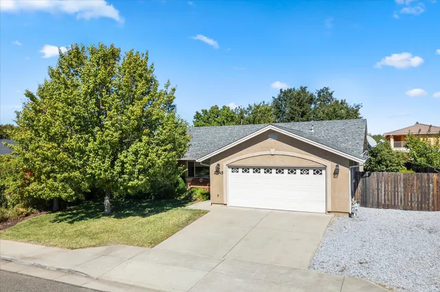 a sign board with a big yard and large tree