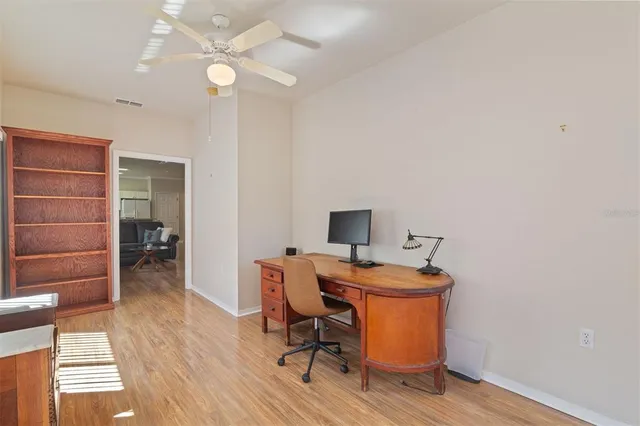 a room with chandelier fan and wooden floor