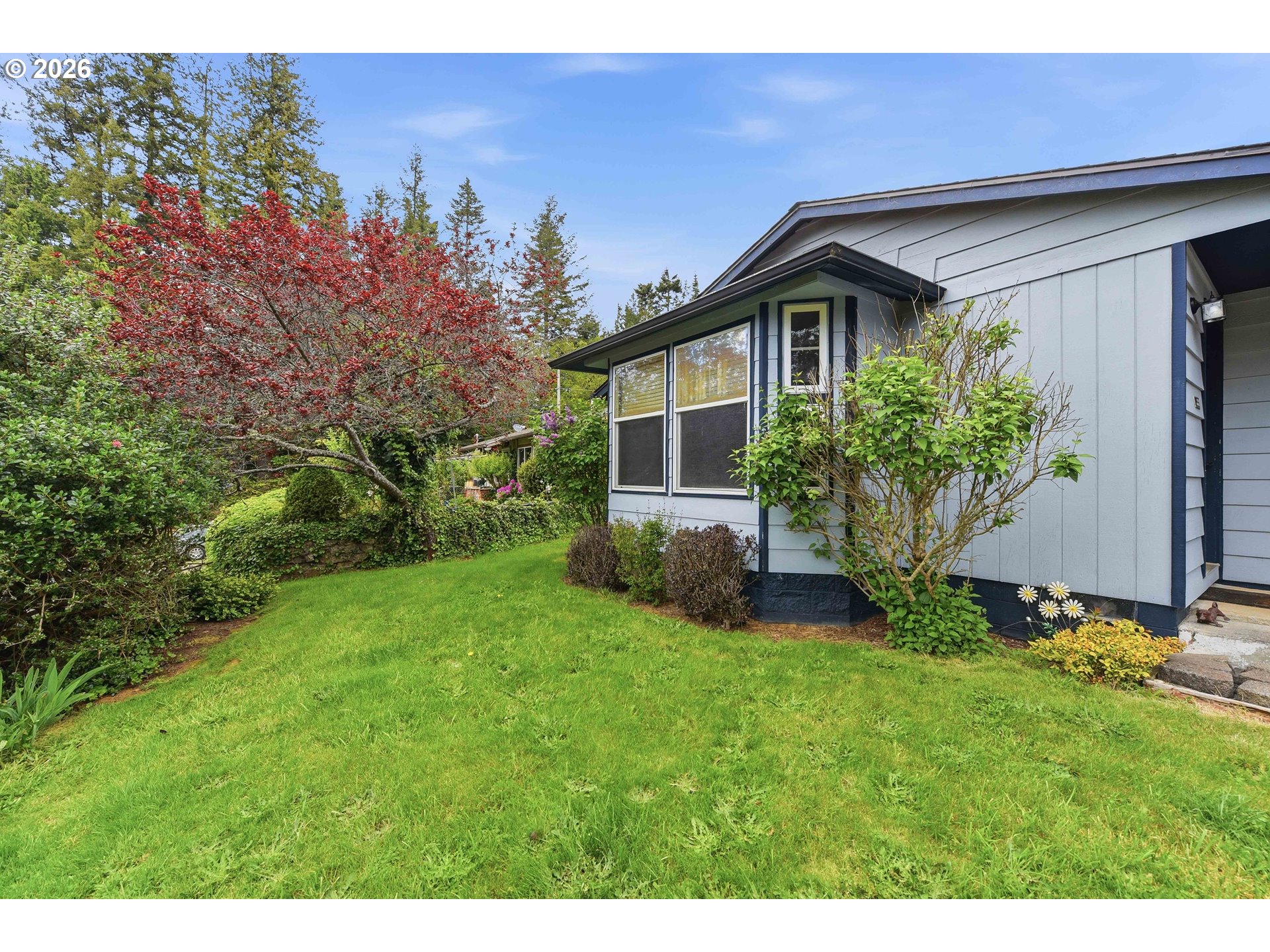 192 North Wood Ridge Road Coquille, OR 97423 - Photo 3 of 42 a front view of a house with a yard and trees