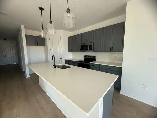 a large kitchen with stainless steel appliances a large counter top a stove a sink and a refrigerator