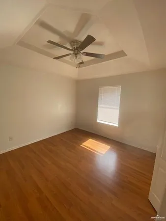 an empty room with wooden floor fan and windows
