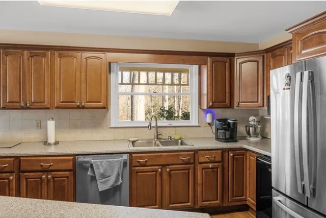 a room with stainless steel appliances kitchen island granite countertop a sink refrigerator and cabinets