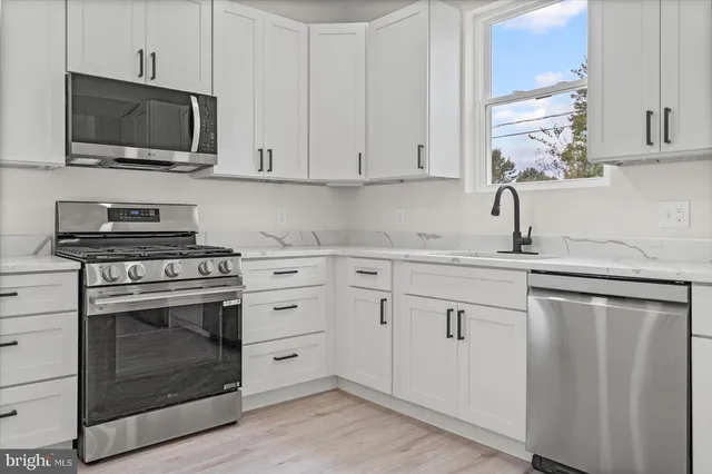 a kitchen with white cabinets stainless steel appliances and sink