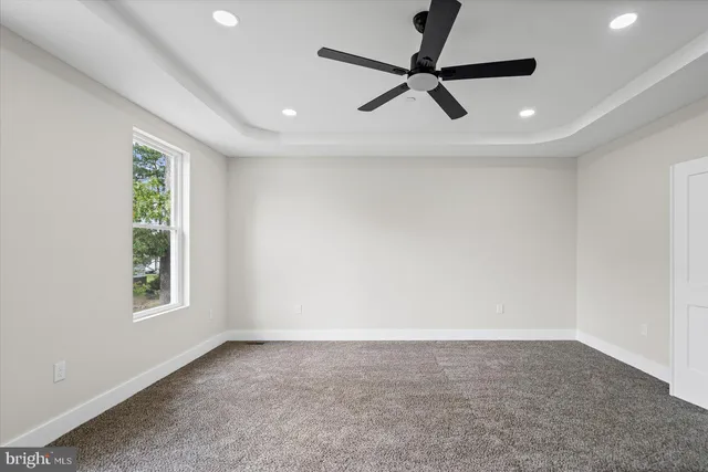 a view of a livingroom with a ceiling fan & windows