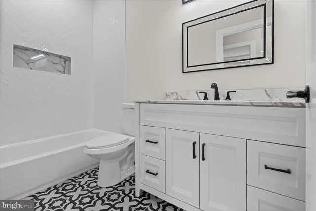 a bathroom with a granite countertop toilet sink and mirror