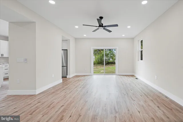 a view of empty room with wooden floor and fan