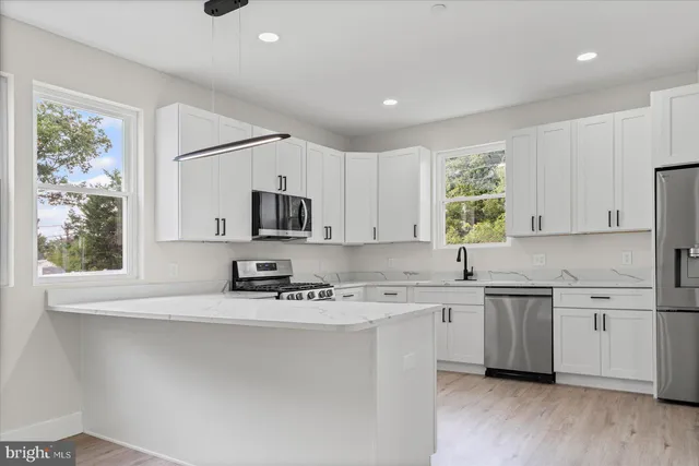 a kitchen with stainless steel appliances a sink a stove a microwave a refrigerator and cabinets