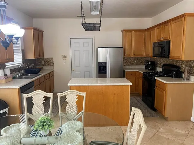 a kitchen with stainless steel appliances a stove a microwave a sink a refrigerator and chairs