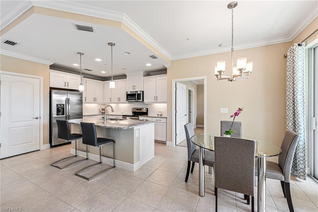 6969 Avalon Circle, Unit 1504 Naples, FL 34112 - Photo 11 of 42 a kitchen with stainless steel appliances kitchen island granite countertop a table chairs and a refrigerator