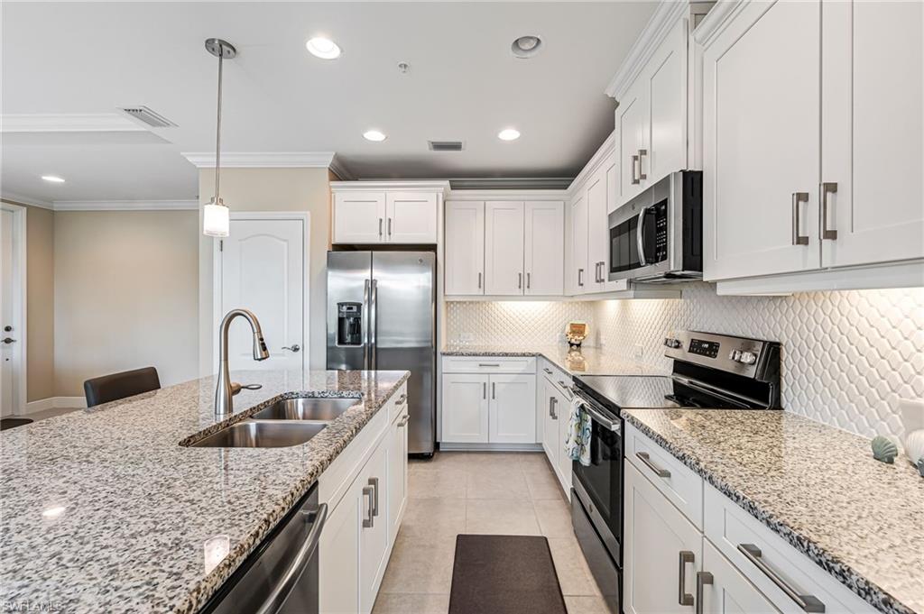 6969 Avalon Circle, Unit 1504 Naples, FL 34112 - Photo 12 of 42 a kitchen with kitchen island granite countertop a sink stainless steel appliances and cabinets