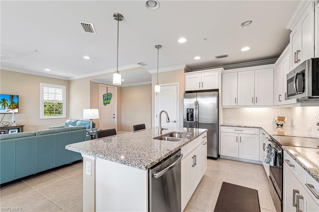 6969 Avalon Circle, Unit 1504 Naples, FL 34112 - Photo 13 of 42 a kitchen with stainless steel appliances granite countertop a sink a stove a refrigerator and island