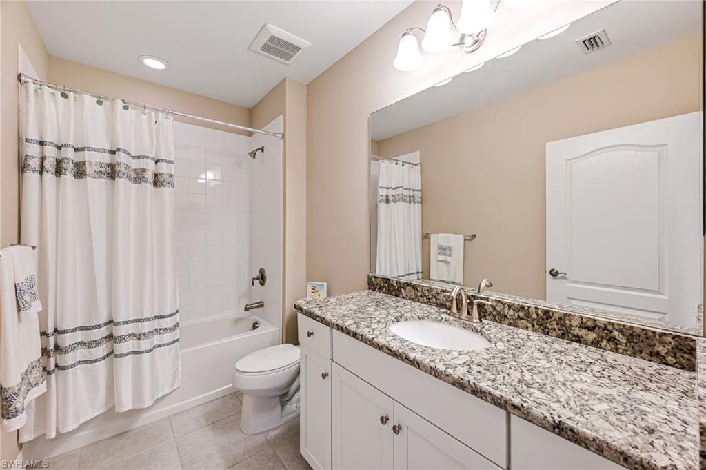 6969 Avalon Circle, Unit 1504 Naples, FL 34112 - Photo 26 of 42 a bathroom with a granite countertop sink a toilet a mirror and shower
