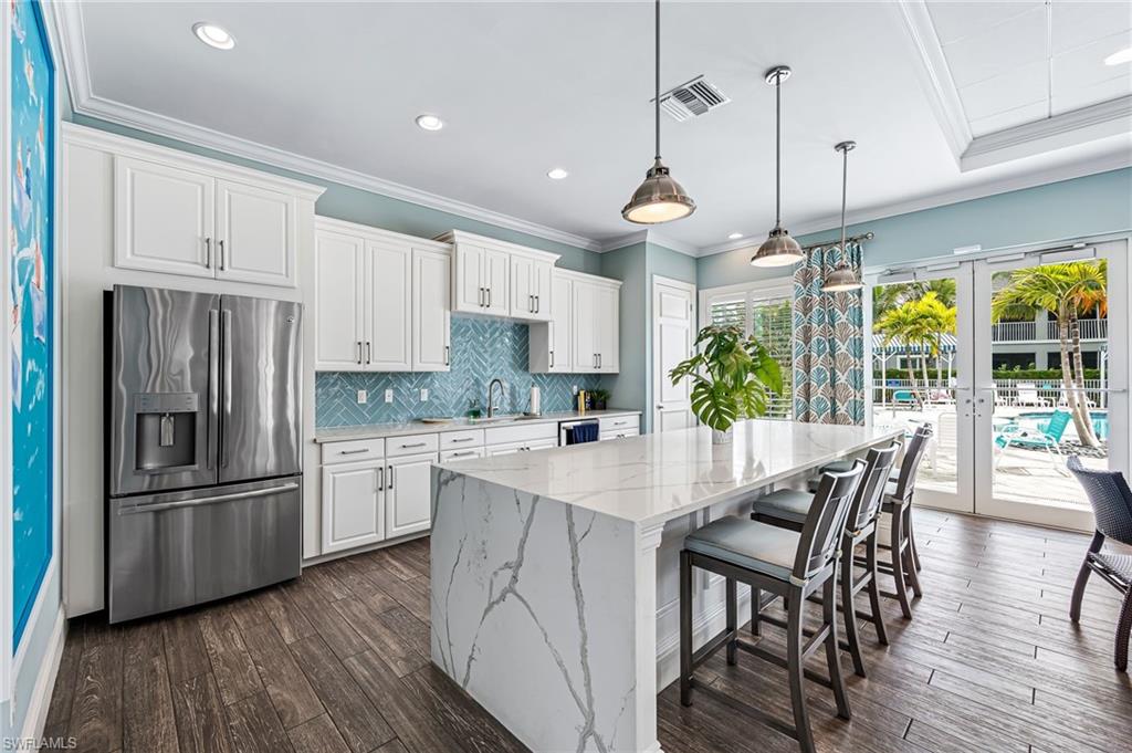 6969 Avalon Circle, Unit 1504 Naples, FL 34112 - Photo 35 of 42 a kitchen with stainless steel appliances a dining table chairs stove refrigerator and cabinets