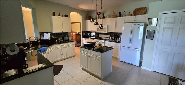 a kitchen with a refrigerator a stove top oven a sink and cabinets
