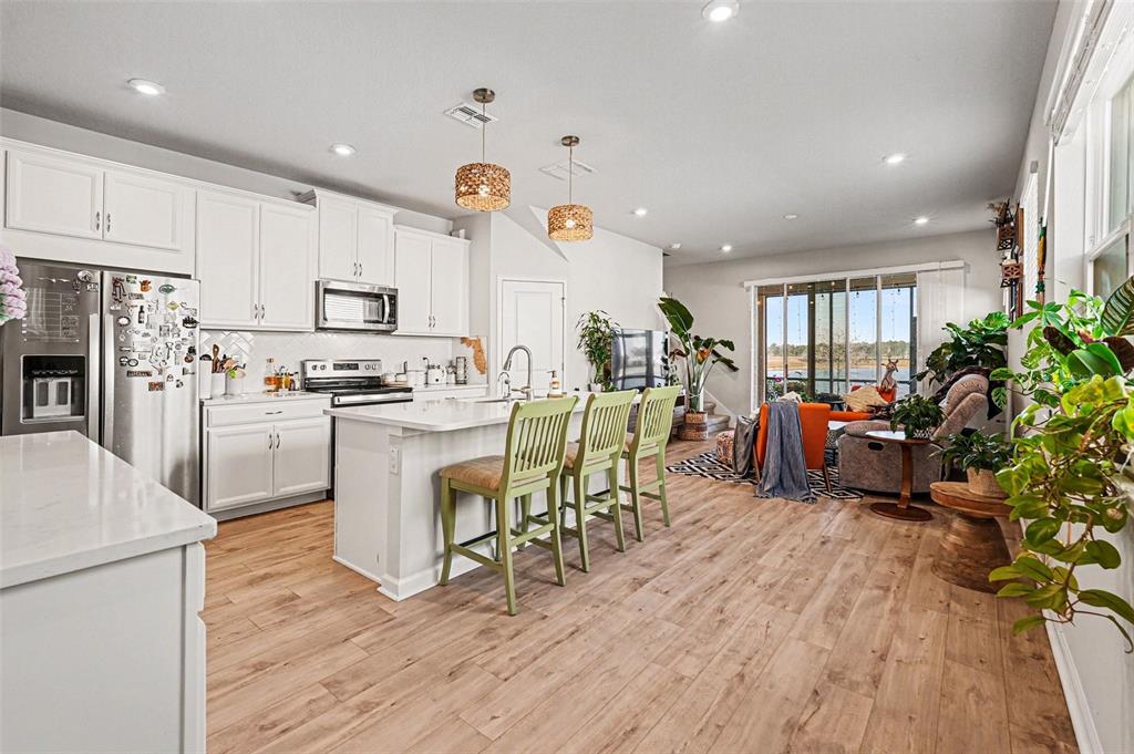 2361 Summerlit Street Lutz, FL 33558 - Photo 8 of 31 a kitchen with stainless steel appliances a stove a refrigerator a kitchen island a stove and a dining table with wooden floor