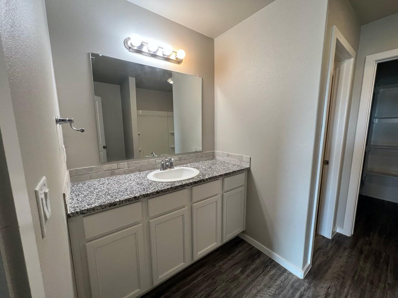 2121 North Avenue J, Unit A Lubbock, TX 79403 - Photo 13 of 20 a bathroom with a granite countertop sink and a mirror
