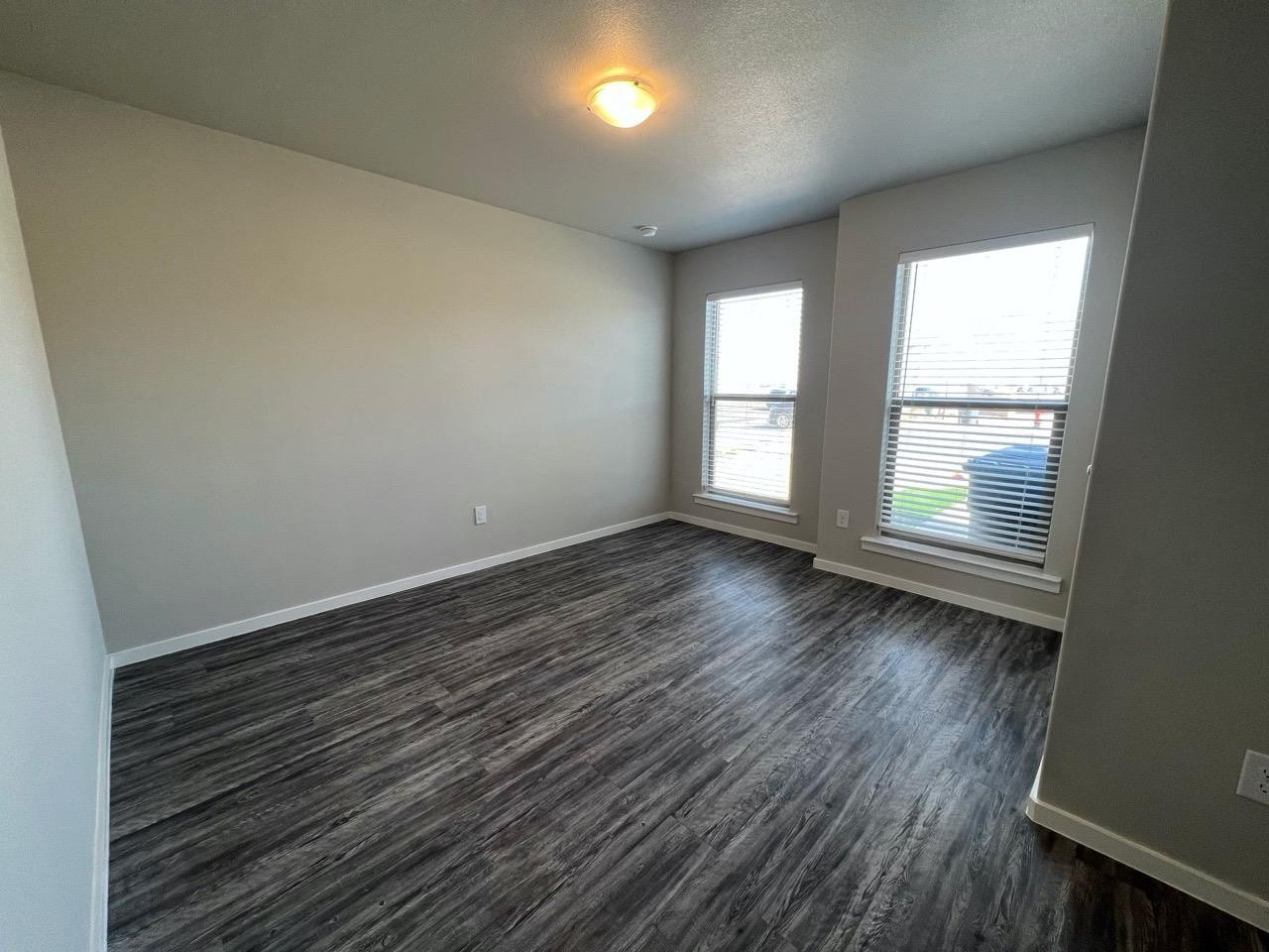2121 North Avenue J, Unit A Lubbock, TX 79403 - Photo 3 of 20 wooden floor in an empty room with a window