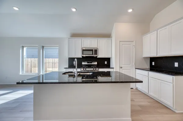 a large kitchen with granite countertop a stove a sink a microwave and cabinets