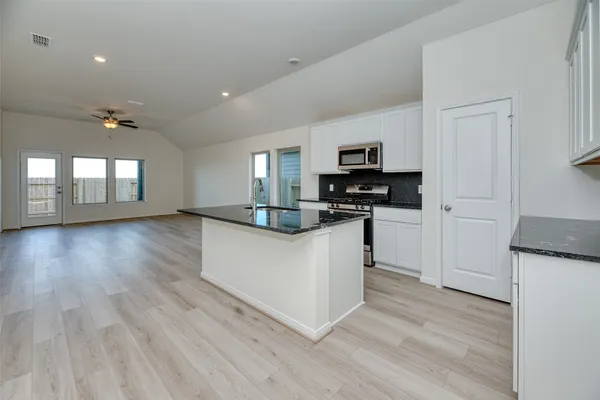 a kitchen with granite countertop a refrigerator and a stove top oven