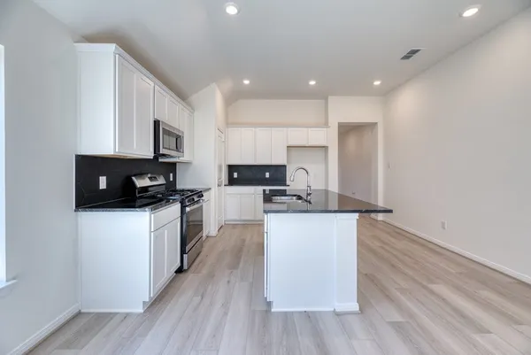 a kitchen with stainless steel appliances kitchen island granite countertop a stove a sink and a microwave