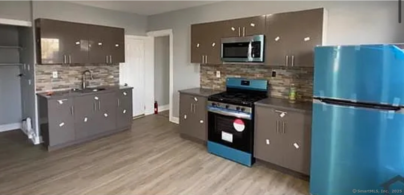 a kitchen with stainless steel appliances granite countertop a refrigerator a stove top oven and sink