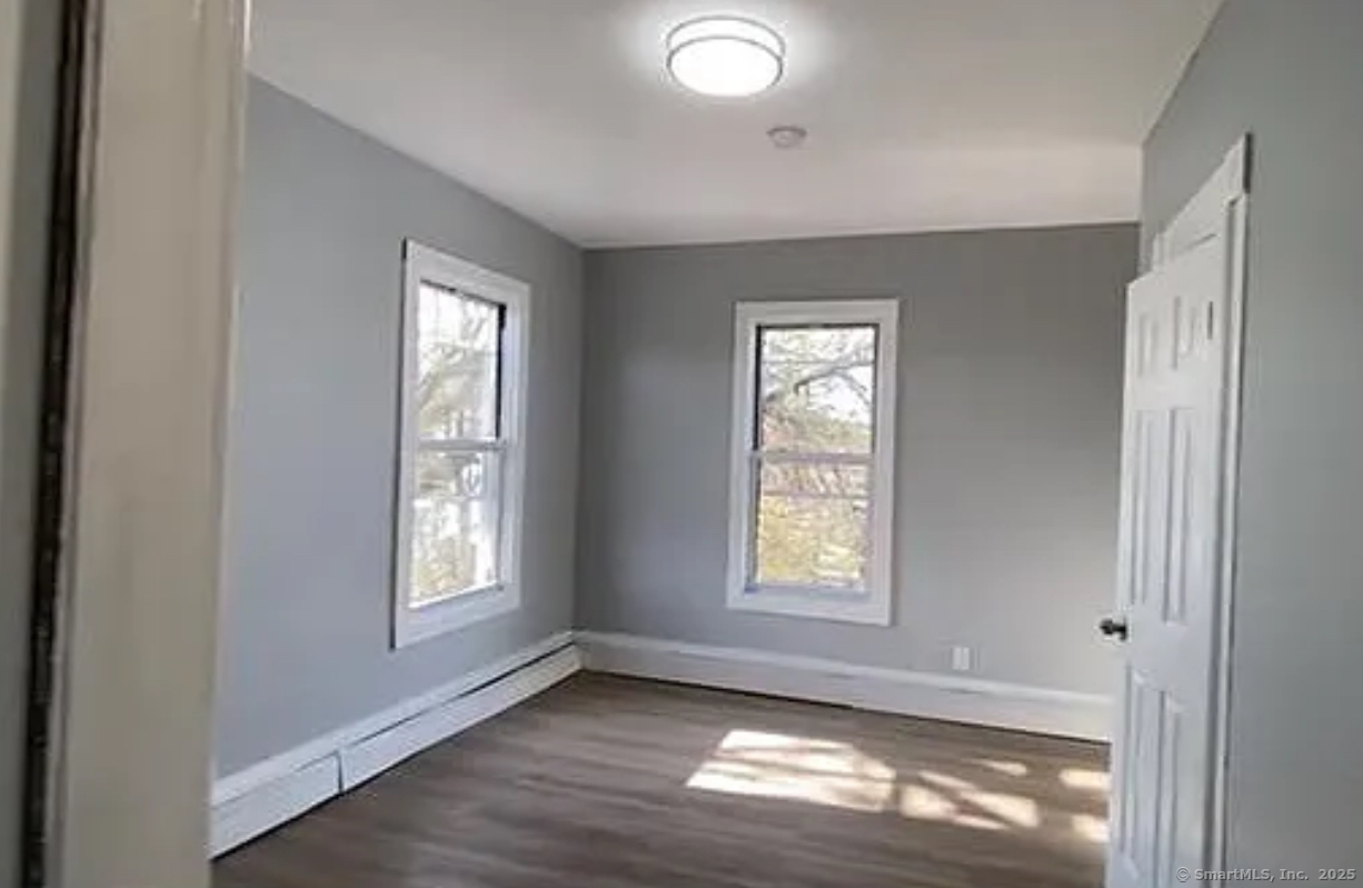 109 Caroline Street Bridgeport, CT 06608 - Photo 2 of 2 an empty room with wooden floor and windows
