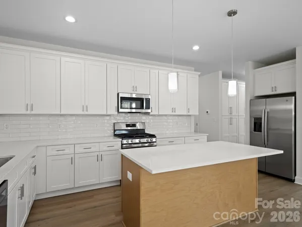 a kitchen with stainless steel appliances a white stove top oven and white cabinets