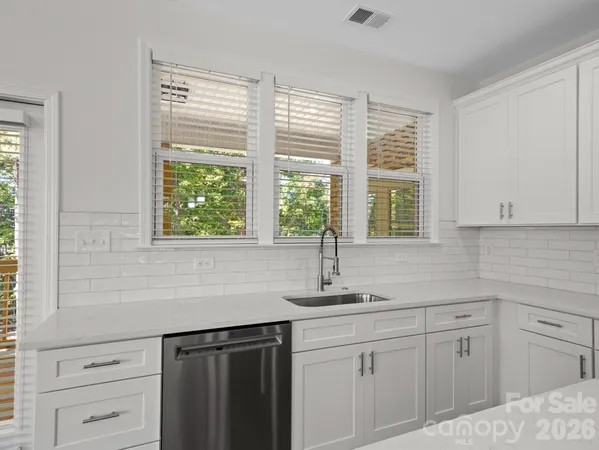 a kitchen with white cabinets and a window