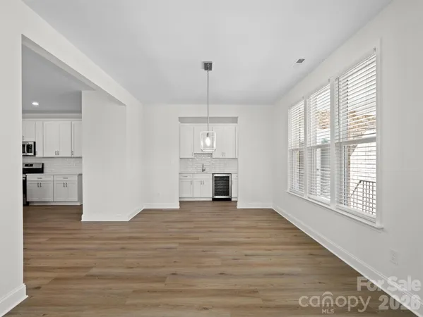a view of a kitchen and an empty room with wooden floor and a kitchen