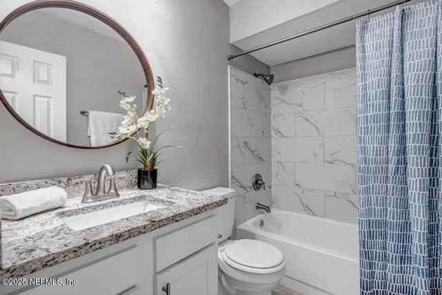a bathroom with a granite countertop sink a toilet and shower
