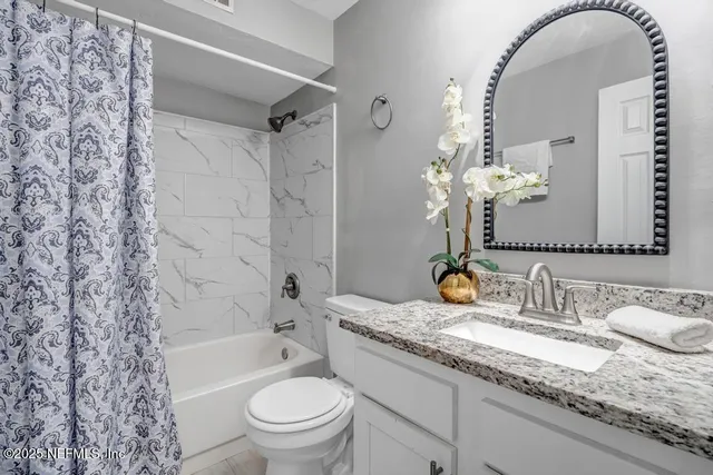 a bathroom with a granite countertop sink a toilet and a mirror
